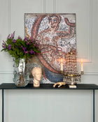 Contemporary mosaic artwork displayed in an elegant interior with classical objects and candlelight.