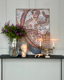 Contemporary mosaic artwork displayed in an elegant interior with classical objects and candlelight.
