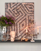 Abstract mosaic artwork displayed in an elegant interior with classical objects and soft candlelight.