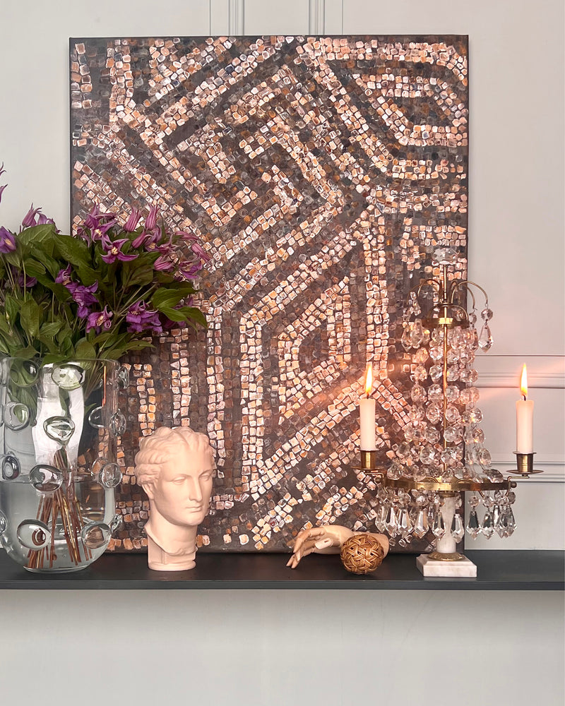 Abstract mosaic artwork displayed in an elegant interior with classical objects and soft candlelight.