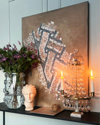 Contemporary abstract mosaic painting styled with flowers, glass objects and neutral architectural background.