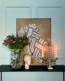 Abstract mosaic artwork displayed in an elegant interior with classical objects and candlelight.