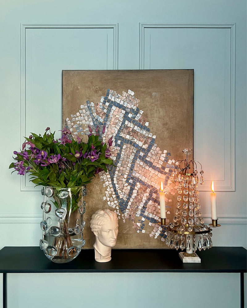 Abstract mosaic artwork displayed in an elegant interior with classical objects and candlelight.