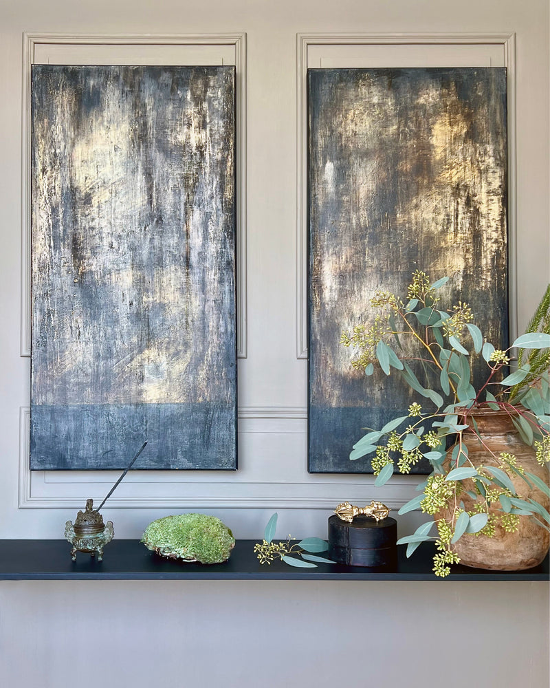 Abstract diptych painting displayed in an interior setting, two vertical panels with dark patina surfaces and earthy tones