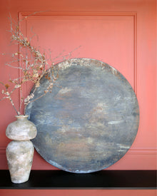 Dark abstract painting on wood shown in a styled interior, layered patina surface with earthy tones
