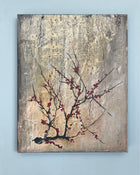 Original square painting displayed on a white wall, featuring a fine branch with red blossoms against a textured grey patina background.